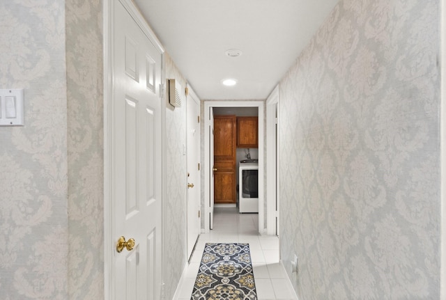 hallway with washer / dryer and light tile patterned flooring