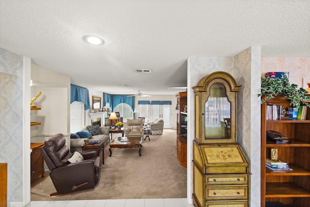 carpeted living area featuring tile patterned flooring, visible vents, a textured ceiling, and ceiling fan