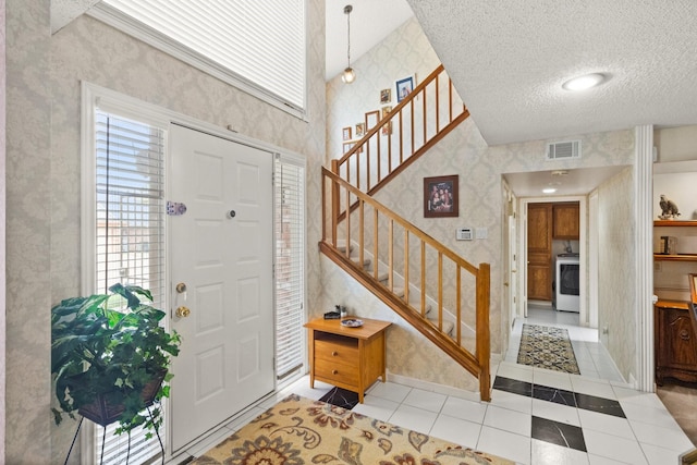 foyer featuring visible vents, wallpapered walls, stairs, tile patterned flooring, and a textured ceiling