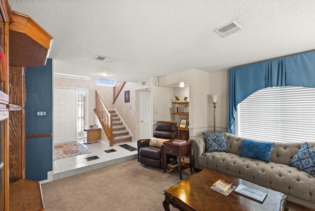 living room with visible vents, a textured ceiling, carpet flooring, and stairs