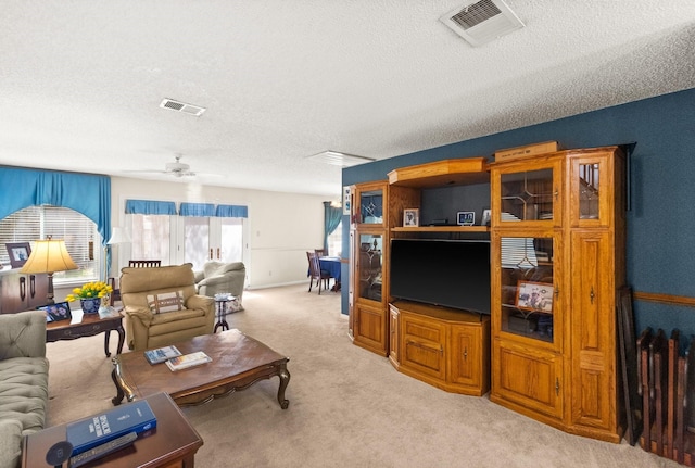 living area with visible vents, light colored carpet, ceiling fan, and a textured ceiling