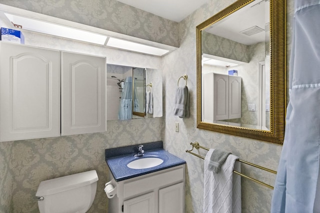 bathroom featuring wallpapered walls, toilet, vanity, and visible vents