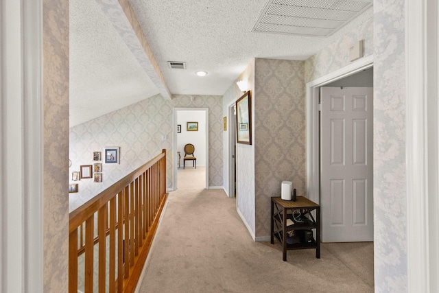 hall with visible vents, carpet flooring, a textured ceiling, and wallpapered walls