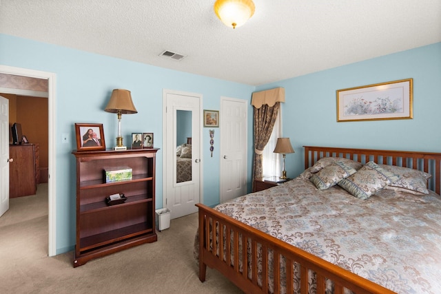 carpeted bedroom featuring visible vents and a textured ceiling