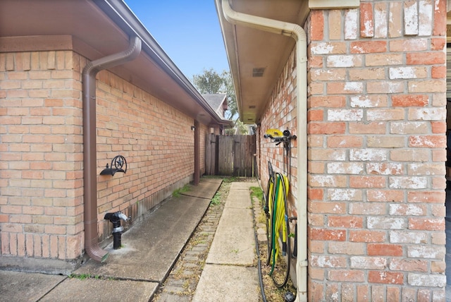 view of property exterior featuring brick siding and fence