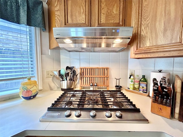 kitchen featuring ventilation hood, backsplash, brown cabinetry, and stainless steel gas cooktop