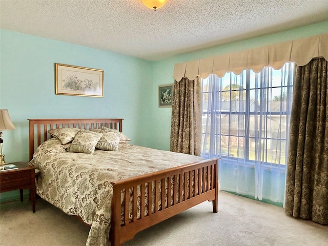 bedroom with a textured ceiling, carpet, and access to outside