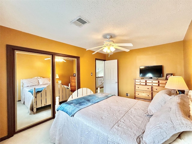 bedroom with carpet flooring, a ceiling fan, visible vents, and a textured ceiling