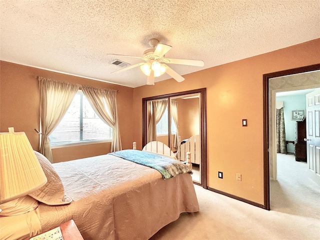 bedroom with visible vents, baseboards, ceiling fan, a textured ceiling, and light colored carpet