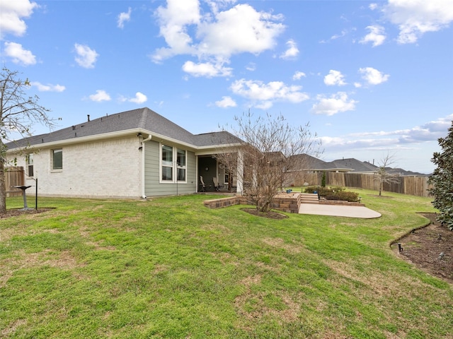 rear view of house featuring a patio area, brick siding, a yard, and fence