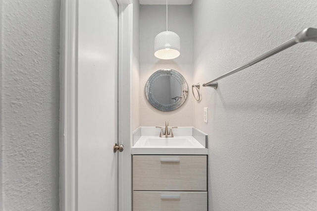 bathroom with a textured wall and vanity