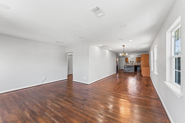 unfurnished living room with visible vents, dark wood finished floors, and baseboards