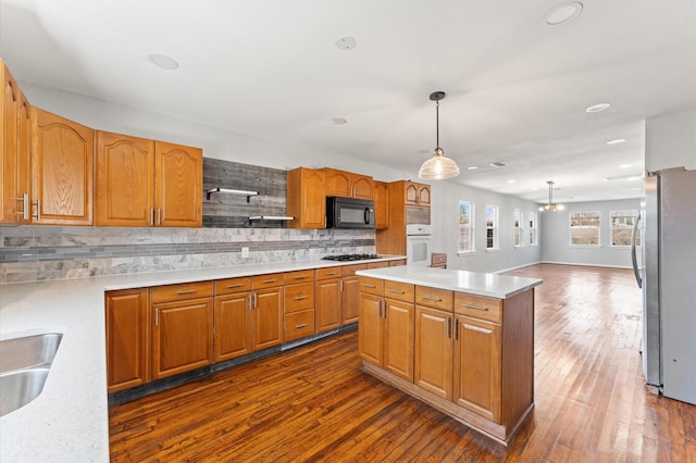 kitchen featuring tasteful backsplash, white oven, freestanding refrigerator, light countertops, and black microwave