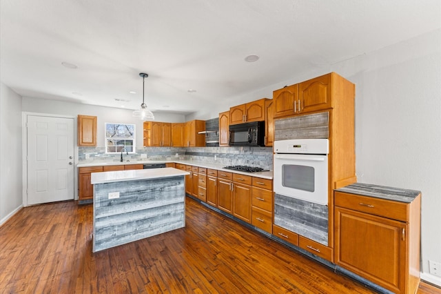 kitchen featuring black appliances, brown cabinetry, dark wood finished floors, and decorative backsplash