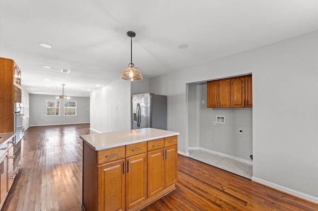 kitchen with hardwood / wood-style flooring, a kitchen island, stainless steel refrigerator with ice dispenser, and light countertops