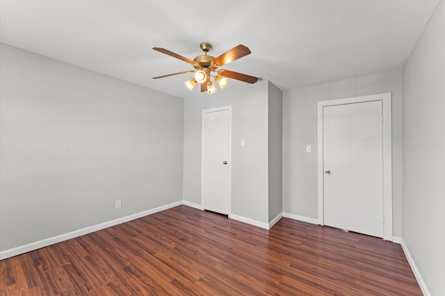 unfurnished bedroom featuring ceiling fan, dark wood-style flooring, and baseboards