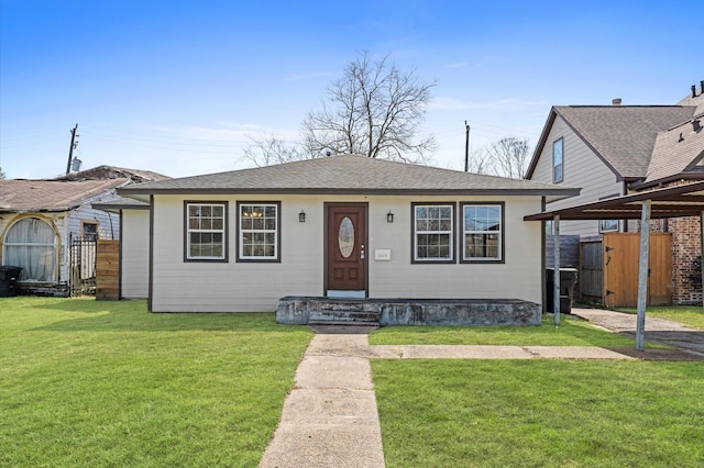 bungalow-style house featuring a shingled roof, fence, and a front lawn