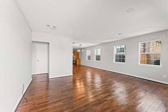 spare room with hardwood / wood-style flooring, baseboards, visible vents, and a notable chandelier