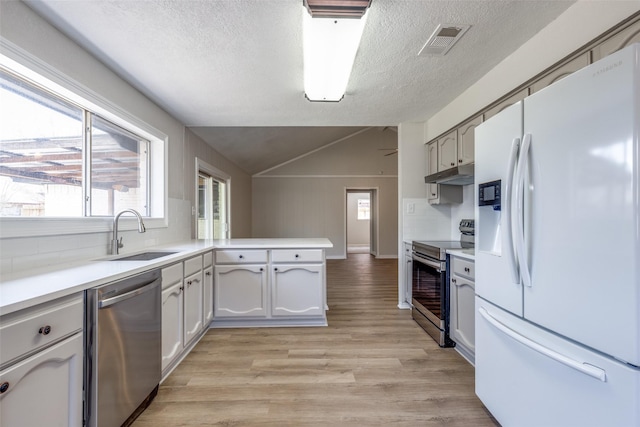 kitchen with visible vents, a peninsula, stainless steel appliances, under cabinet range hood, and a sink