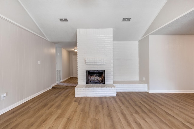 unfurnished living room with a fireplace, visible vents, and wood finished floors