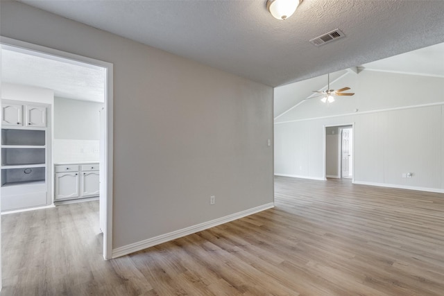 spare room featuring light wood finished floors, visible vents, and a textured ceiling