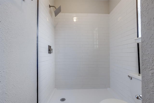 bathroom featuring a textured wall, a shower stall, and toilet