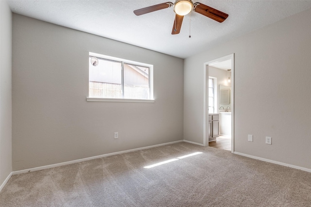 carpeted spare room featuring baseboards and a ceiling fan