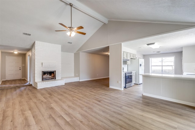 unfurnished living room with lofted ceiling with beams, light wood-type flooring, a brick fireplace, and visible vents