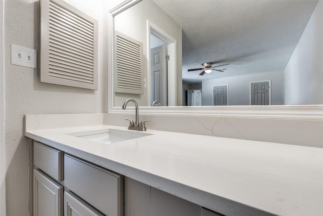 bathroom with a textured wall, a ceiling fan, a textured ceiling, and vanity