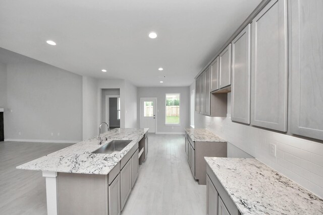 11926 Maple Oak Dr, Houston, TX 77066 - kitchen featuring light wood finished floors, a kitchen island with sink, recessed lighting, light stone counters, and tasteful backsplash