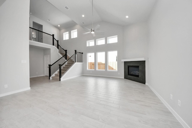 11926 Maple Oak Dr, Houston, TX 77066 - unfurnished living room with a ceiling fan, a glass covered fireplace, high vaulted ceiling, stairs, and recessed lighting