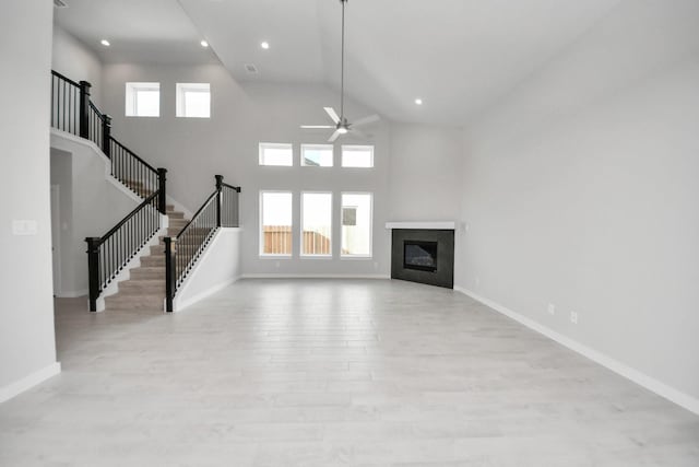 11926 Maple Oak Dr, Houston, TX 77066 - unfurnished living room featuring a ceiling fan, wood finished floors, stairs, high vaulted ceiling, and a glass covered fireplace