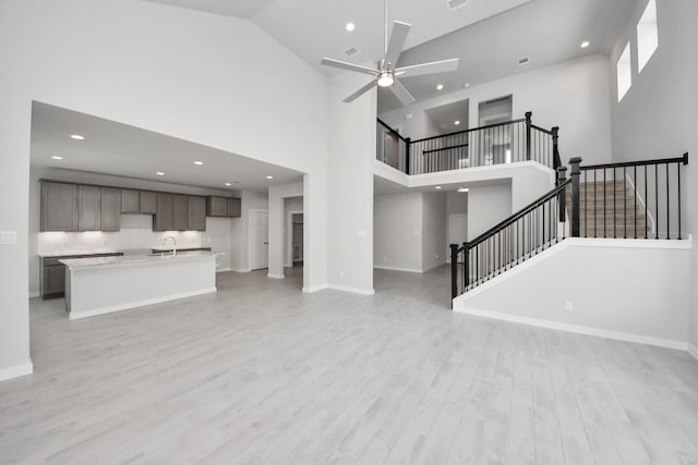 11926 Maple Oak Dr, Houston, TX 77066 - unfurnished living room with light wood-style floors, recessed lighting, a ceiling fan, stairs, and a high ceiling