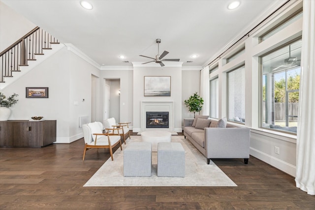 living area with ornamental molding, a ceiling fan, baseboards, and wood finished floors