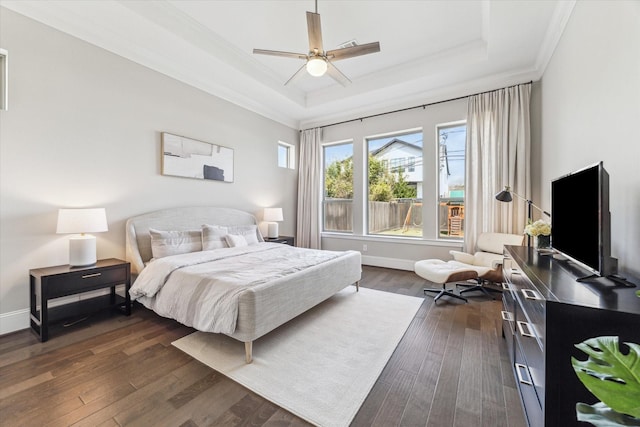 bedroom with dark wood-style floors, a tray ceiling, ornamental molding, and baseboards