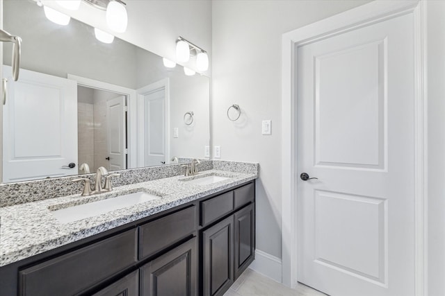 full bath with tile patterned floors, a sink, baseboards, and double vanity