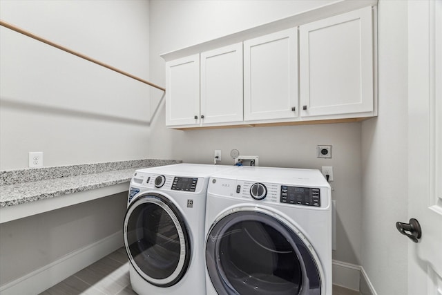 laundry room featuring cabinet space, baseboards, and washing machine and clothes dryer