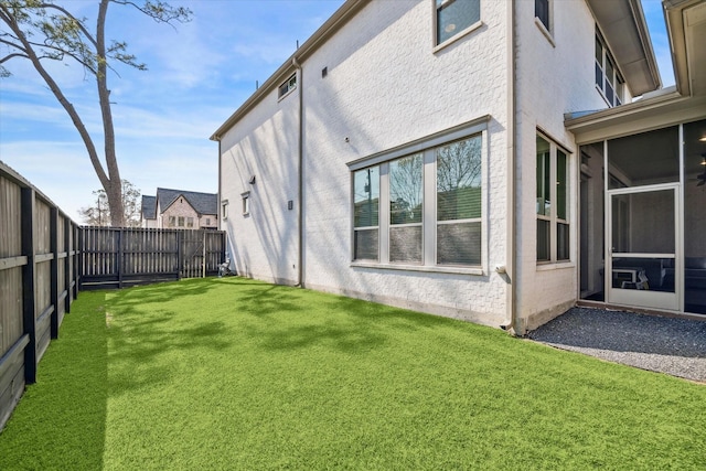 exterior space with a sunroom, a fenced backyard, a lawn, and stucco siding