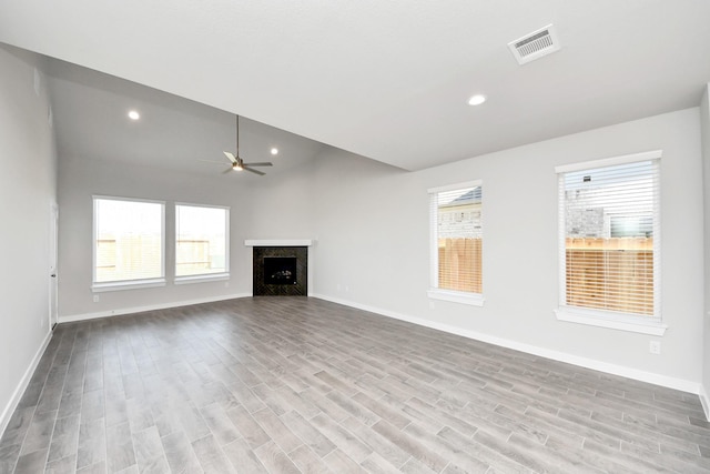 unfurnished living room with visible vents, plenty of natural light, wood finished floors, and a premium fireplace