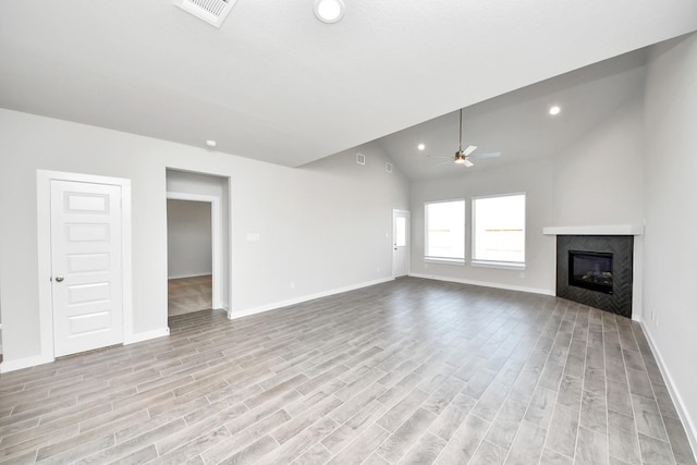 unfurnished living room featuring light wood finished floors, visible vents, lofted ceiling, a glass covered fireplace, and a ceiling fan