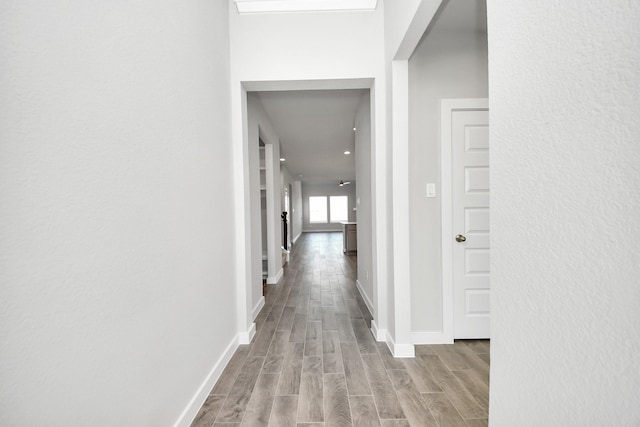 corridor with wood finished floors and baseboards