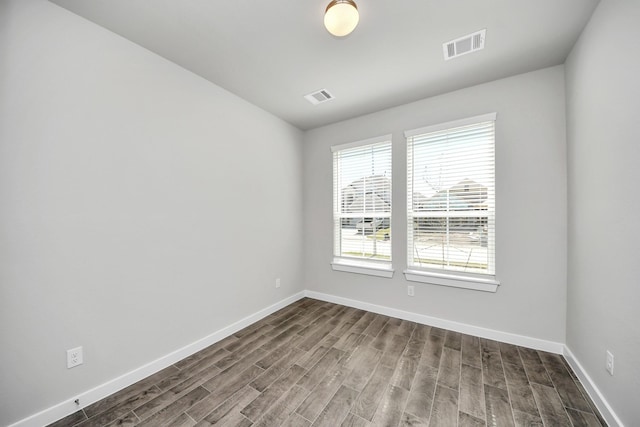 unfurnished room with baseboards, visible vents, and dark wood-style flooring