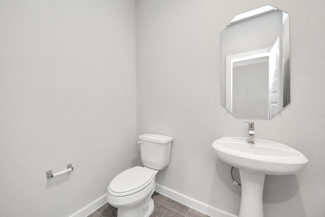 half bathroom featuring tile patterned flooring, toilet, and baseboards