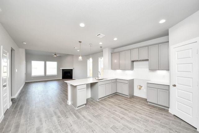 kitchen with visible vents, a fireplace, a sink, gray cabinetry, and open floor plan