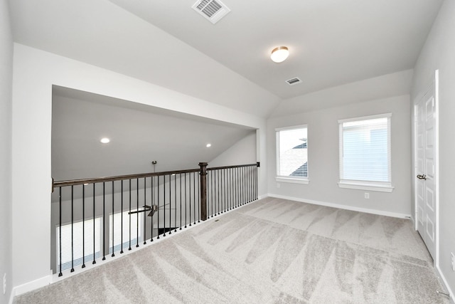 carpeted empty room featuring vaulted ceiling, baseboards, and visible vents