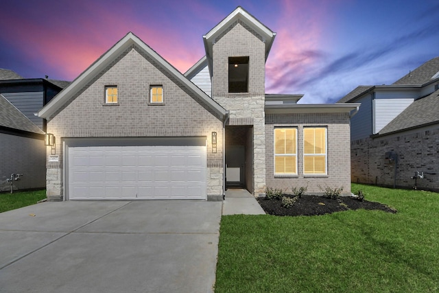 view of front facade featuring stone siding, a lawn, brick siding, and driveway