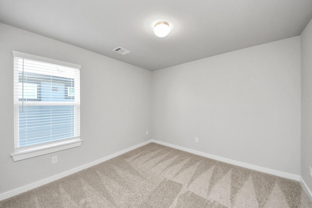 carpeted spare room featuring baseboards and visible vents