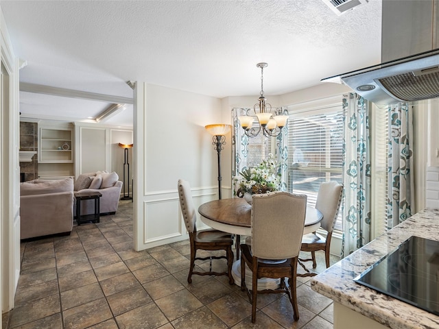 dining area featuring visible vents, a textured ceiling, built in shelves, a chandelier, and a decorative wall