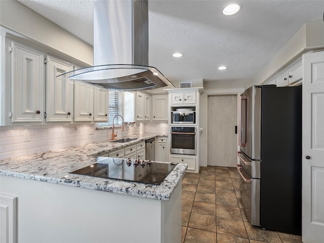 kitchen featuring island range hood, a peninsula, stainless steel appliances, white cabinetry, and a sink