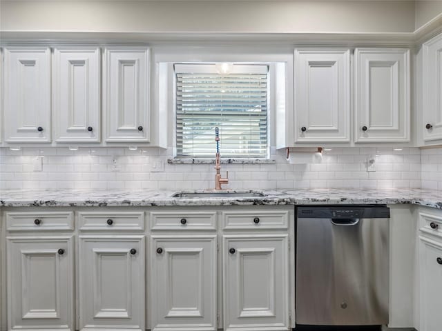 kitchen with decorative backsplash, stainless steel dishwasher, white cabinets, a sink, and light stone countertops